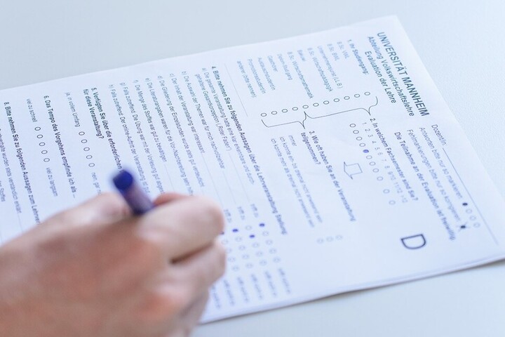 Evaluation form that is filled in with a blue pen. A hand holding the pen is at the bottom left of the picture.
